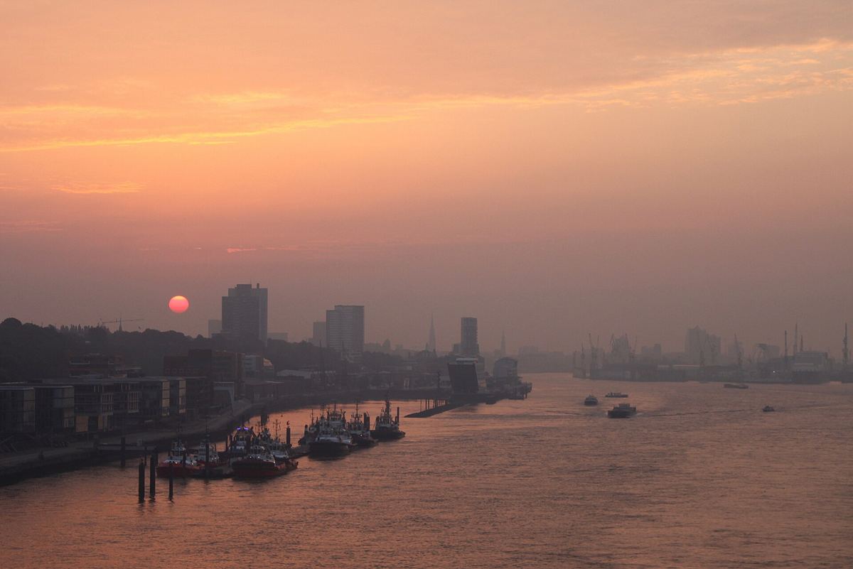 Sonnenaufgang über der Elbe in Hamburg mit Hafenkränen am Horizont